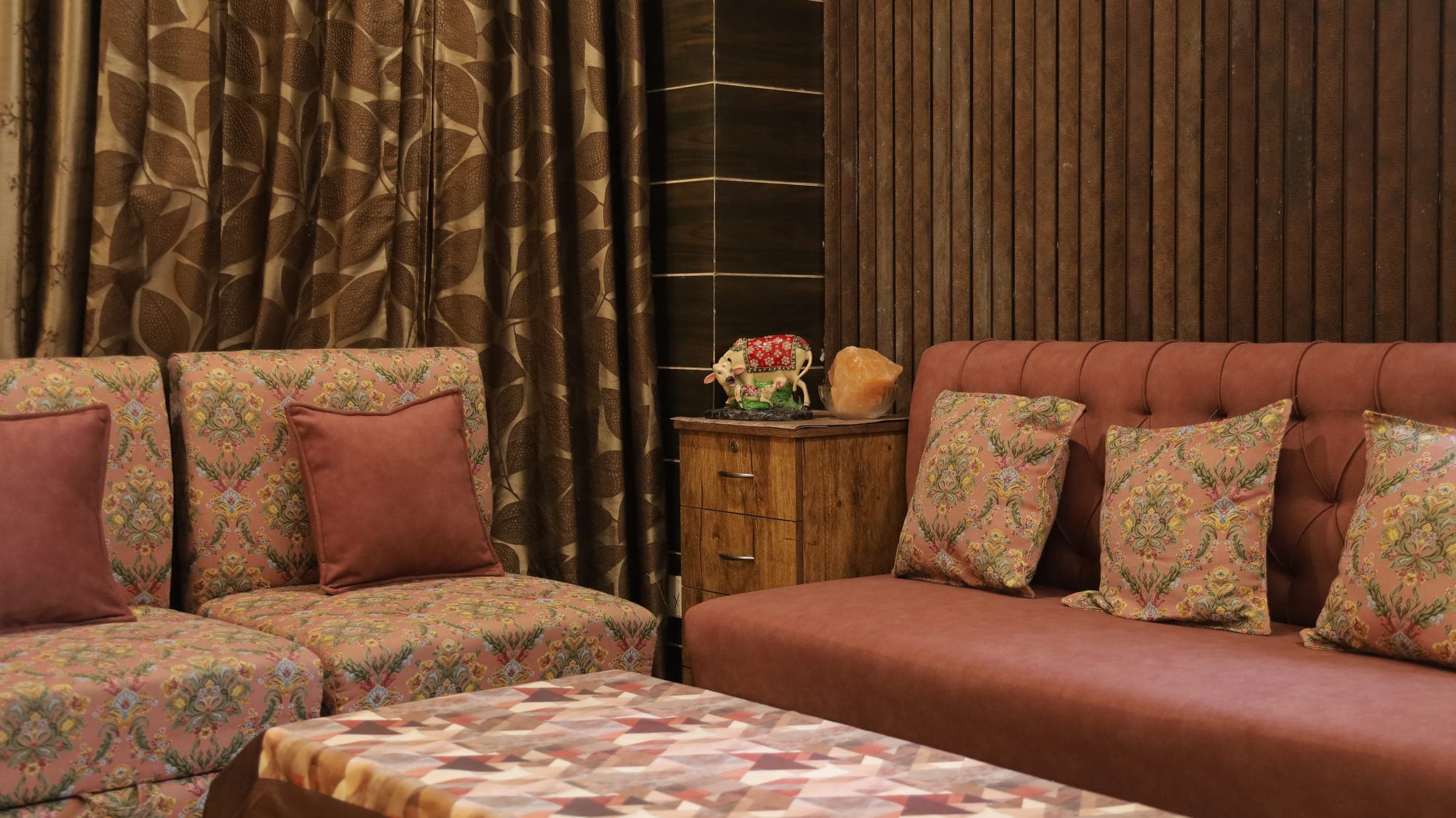 A warm sitting room by the studio — patterned settees, a rust velvet couch and a fluted wood wall