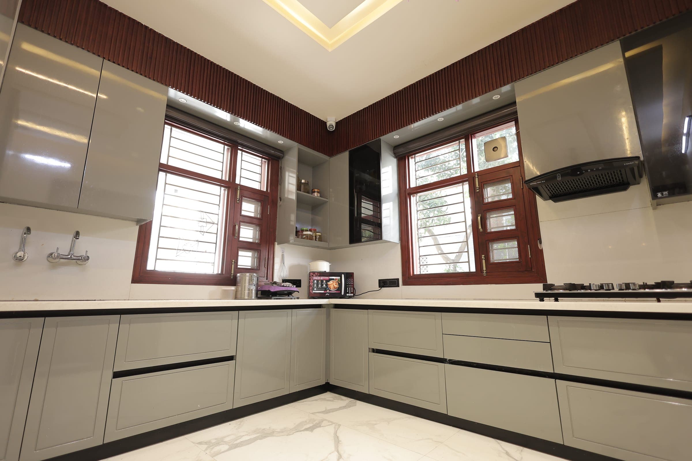 A finished corner kitchen with grey cabinetry and a marble-look worktop